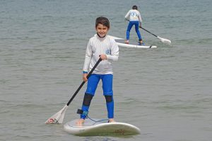 ילד חותר על גלשן בים כחול.