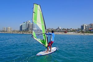 גולש על גלשן רוח עם מפרש גדול בים ביום בהיר.